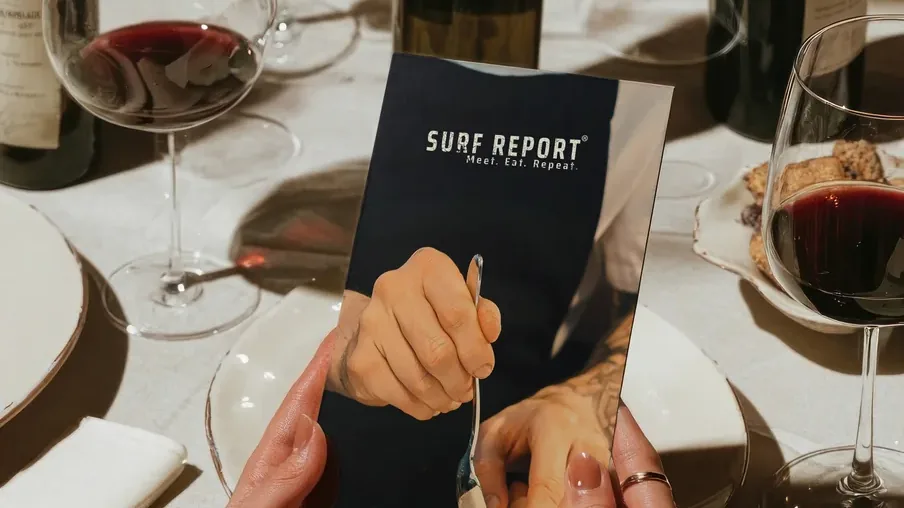 Surf Report menu in a guest’s hands at a set table