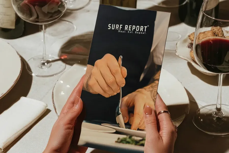 A Surf Report menu held open at a set table