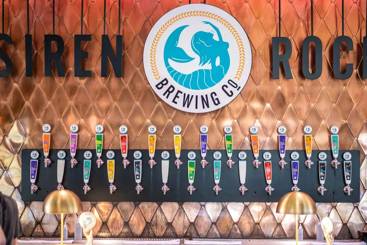 A brick and patterned tile wall carrying an illuminated sign above a bar