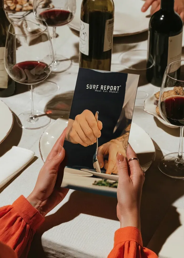 Guests holding a printed menu at a set table