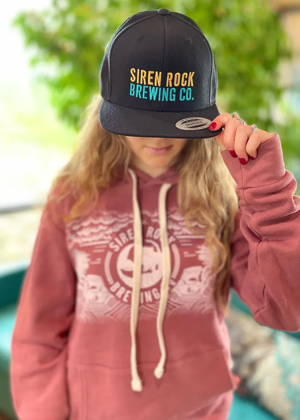 A hospitality brand worn out the door on a cap and hoodie
