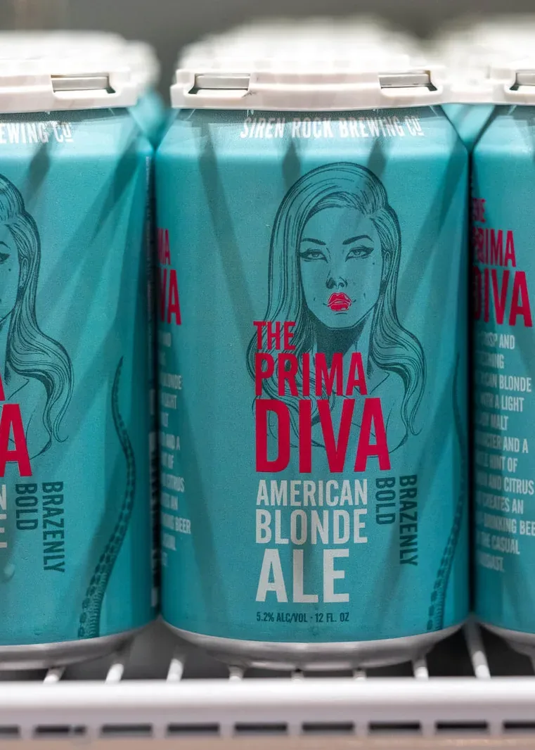 Siren Rock Prima Diva blonde ale cans on a cooler shelf